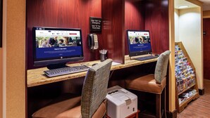 Deux postes de travail informatiques, chacun équipé d’une chaise, d’une imprimante et d’un téléphone, sont installés sur un bureau.