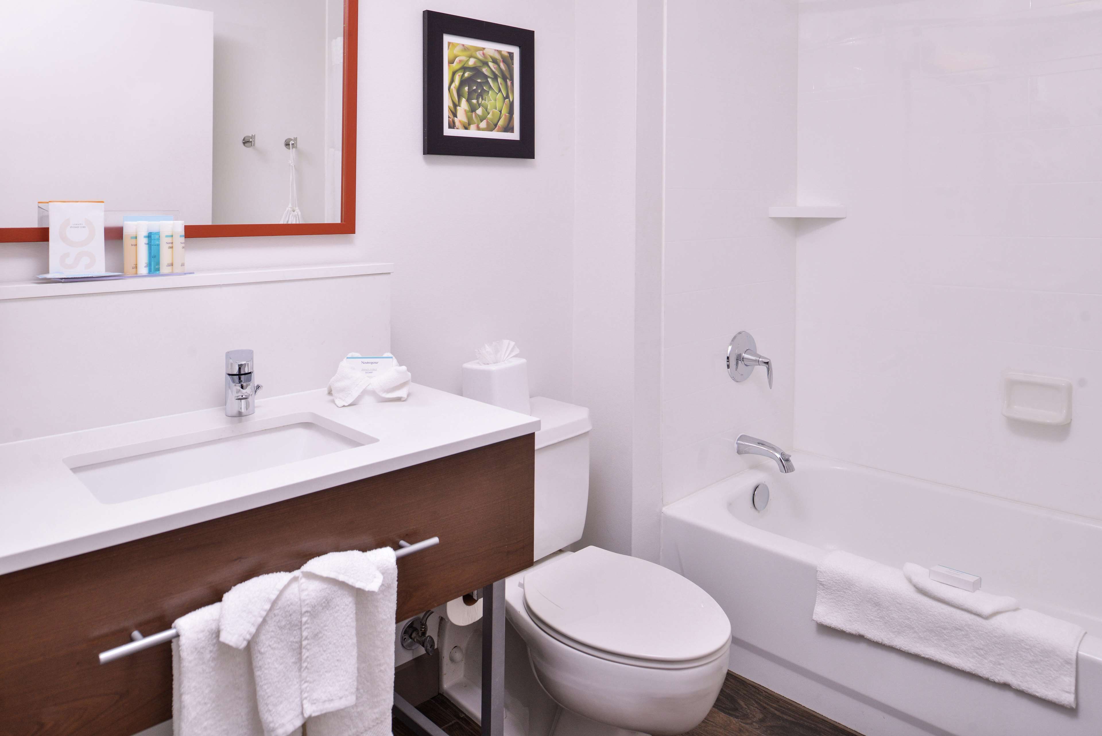 Un baño moderno con lavamanos, tocador, inodoro y bañera blancos.