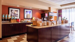 Un espace pour le petit-déjeuner à l’hôtel, doté d’un grand comptoir, de distributeurs de café et d’un téléviseur.