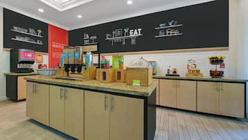 Un área de cocina moderna con armarios de madera, encimeras de granito y diversos alimentos a la vista.