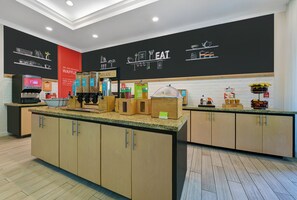 Un área de cocina moderna con armarios de madera, encimeras de granito y diversos alimentos a la vista.