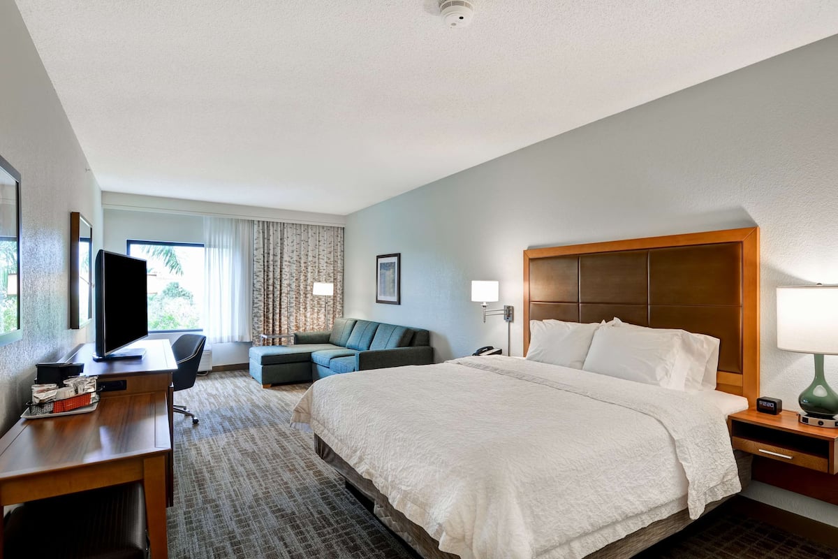 Habitación de hotel con cama, escritorio, televisión y zona de estar.