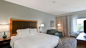 Una habitación de hotel con una cama grande, un escritorio, una silla y un televisor.