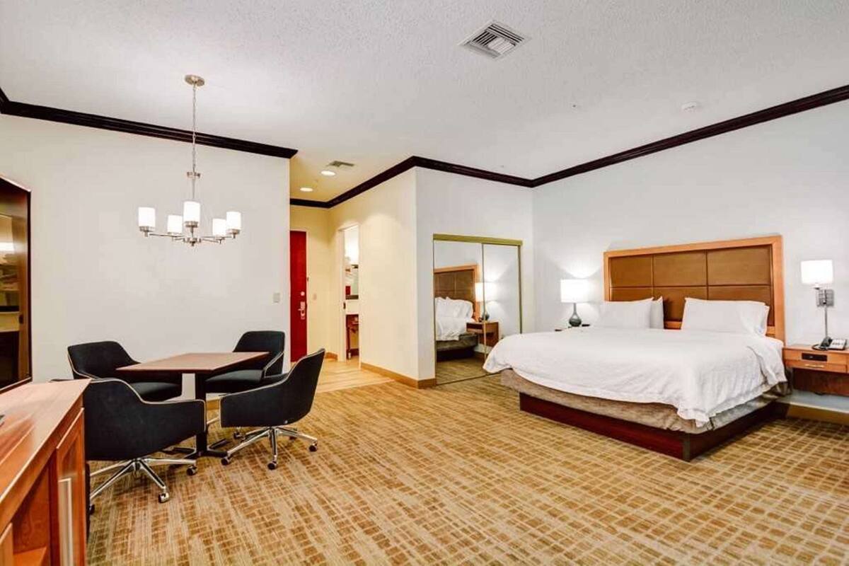 Habitación de hotel con cama, escritorio, sillas y candelabro.