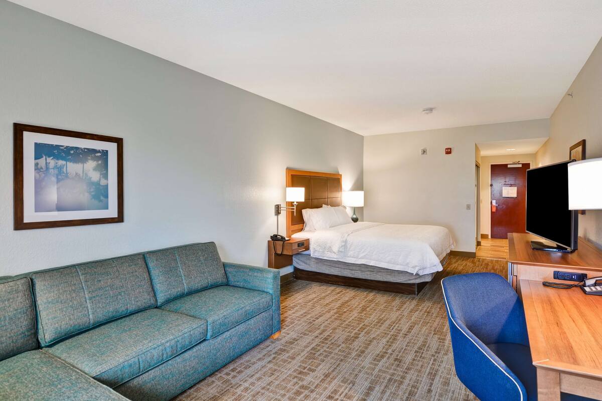 Una habitación de hotel con cama, sofá, escritorio y televisión.