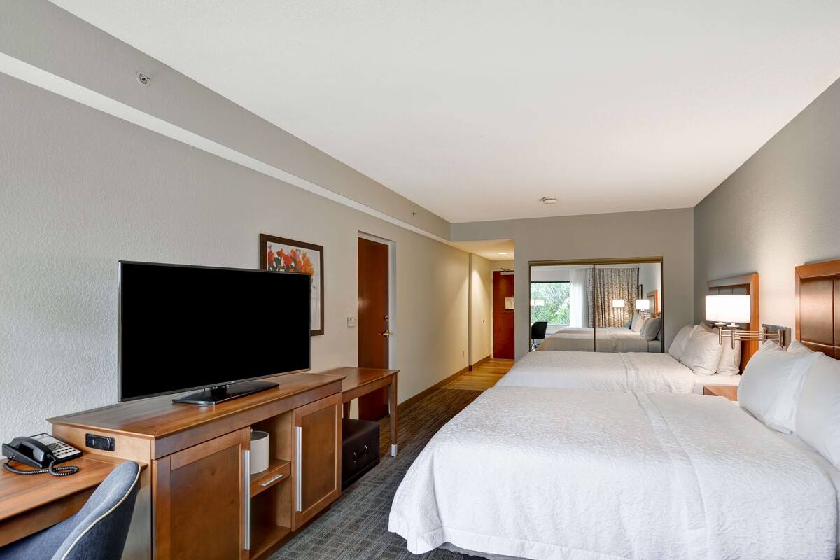Una habitación de hotel con una cama grande, un escritorio, un televisor de pantalla plana, un teléfono y un armario.