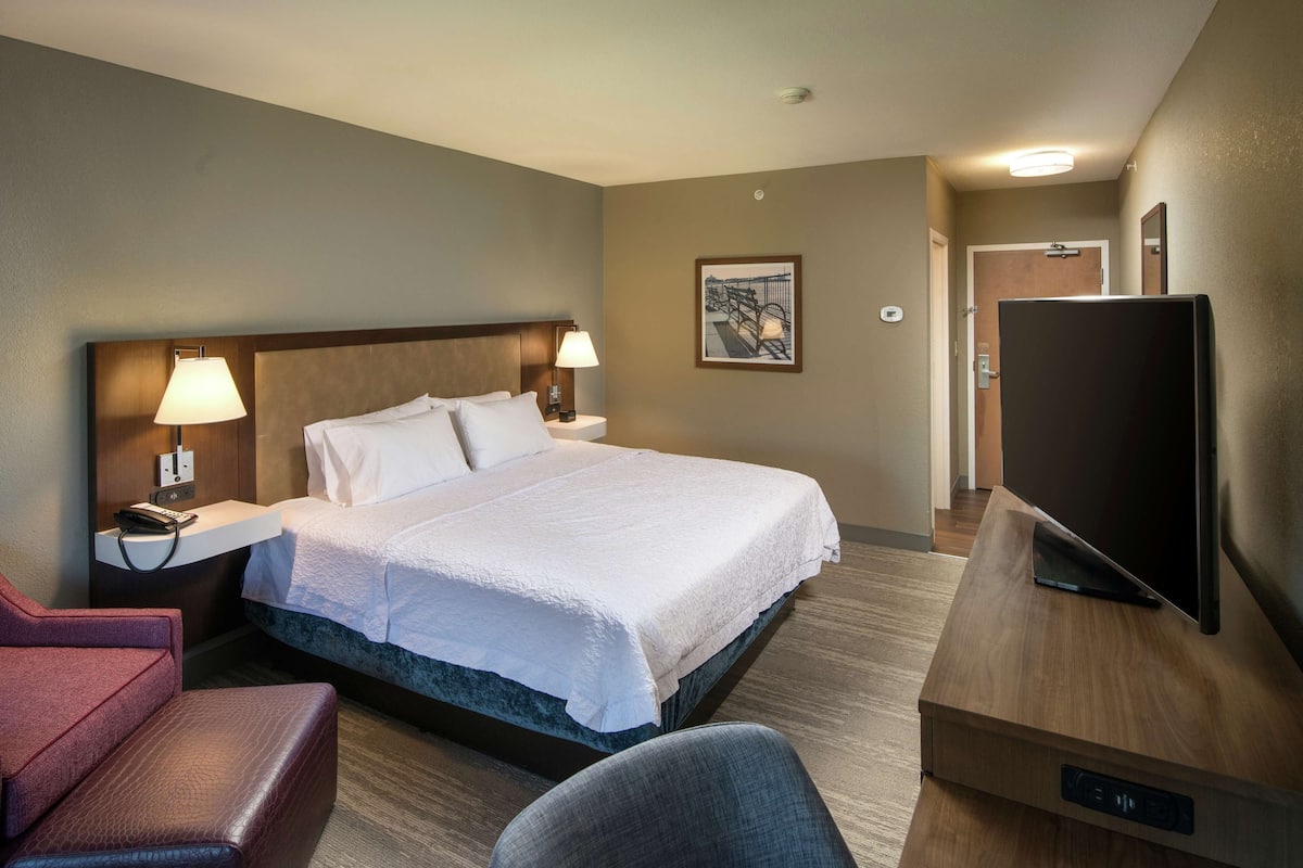 A hotel room with a bed, a TV, a desk, and a chair.