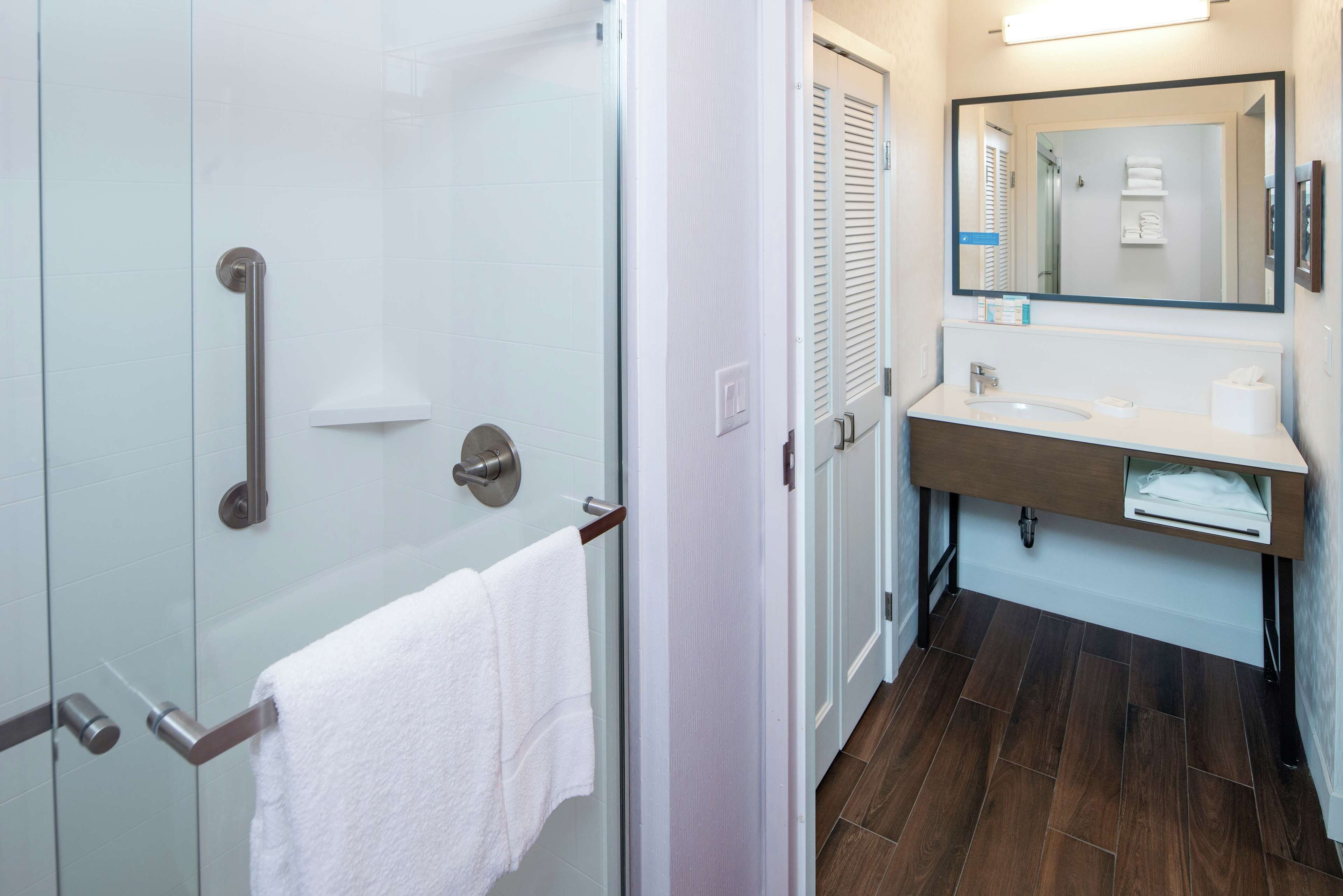 A modern bathroom with a glass shower enclosure, a white sink, and a mirror above the vanity.