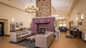A spacious living area with a fireplace, sofas, and a chandelier. - Hampton Inn & Suites Binghamton/Vestal (Vestal)