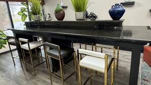 Una cocina moderna con una isla central, taburetes de bar y plantas en macetas.