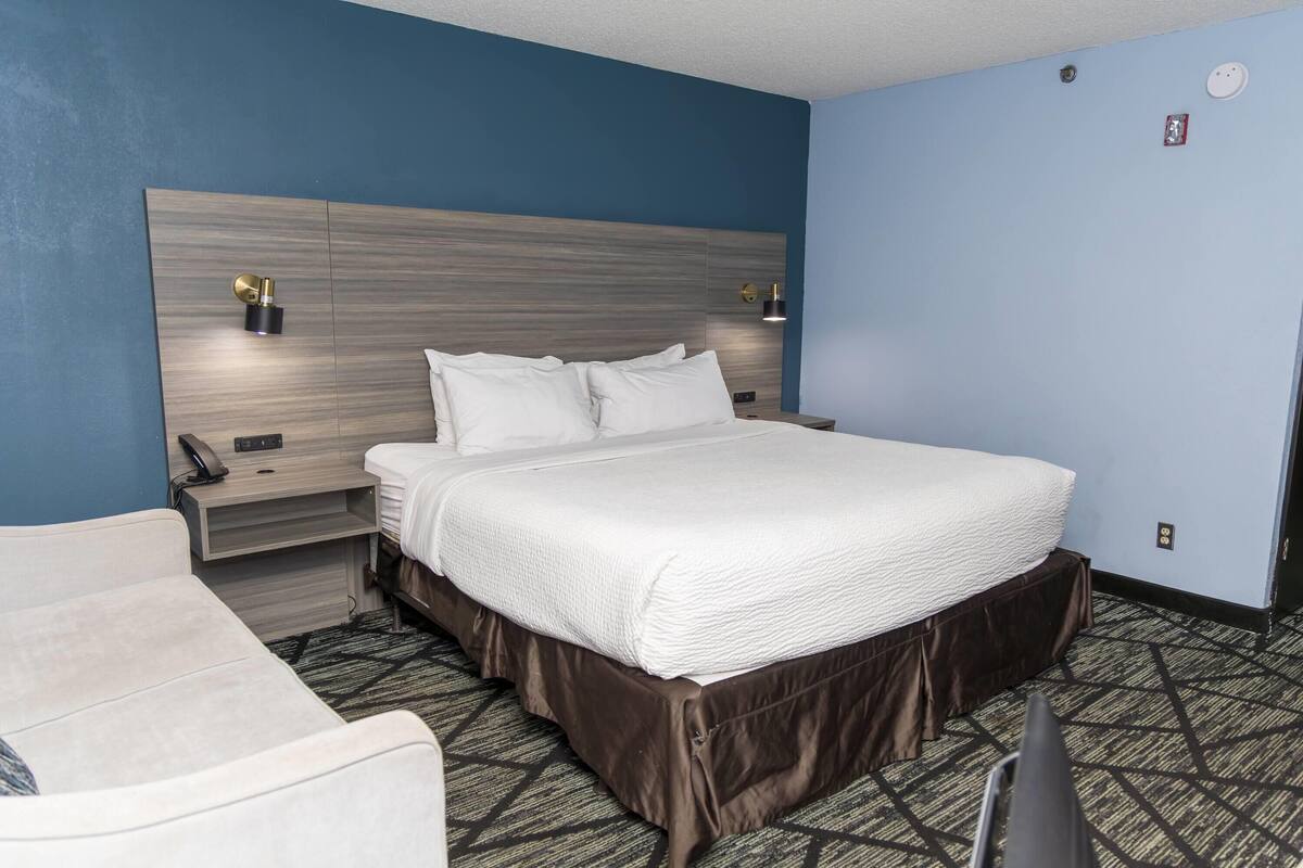 Une chambre d’hôtel avec un grand lit, des tables de chevet, un bureau et une chaise.