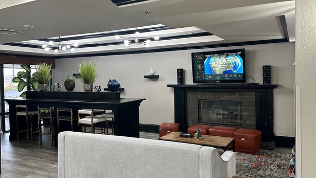 Una sala de estar moderna con chimenea, un televisor montado encima y una zona de comedor con barra.