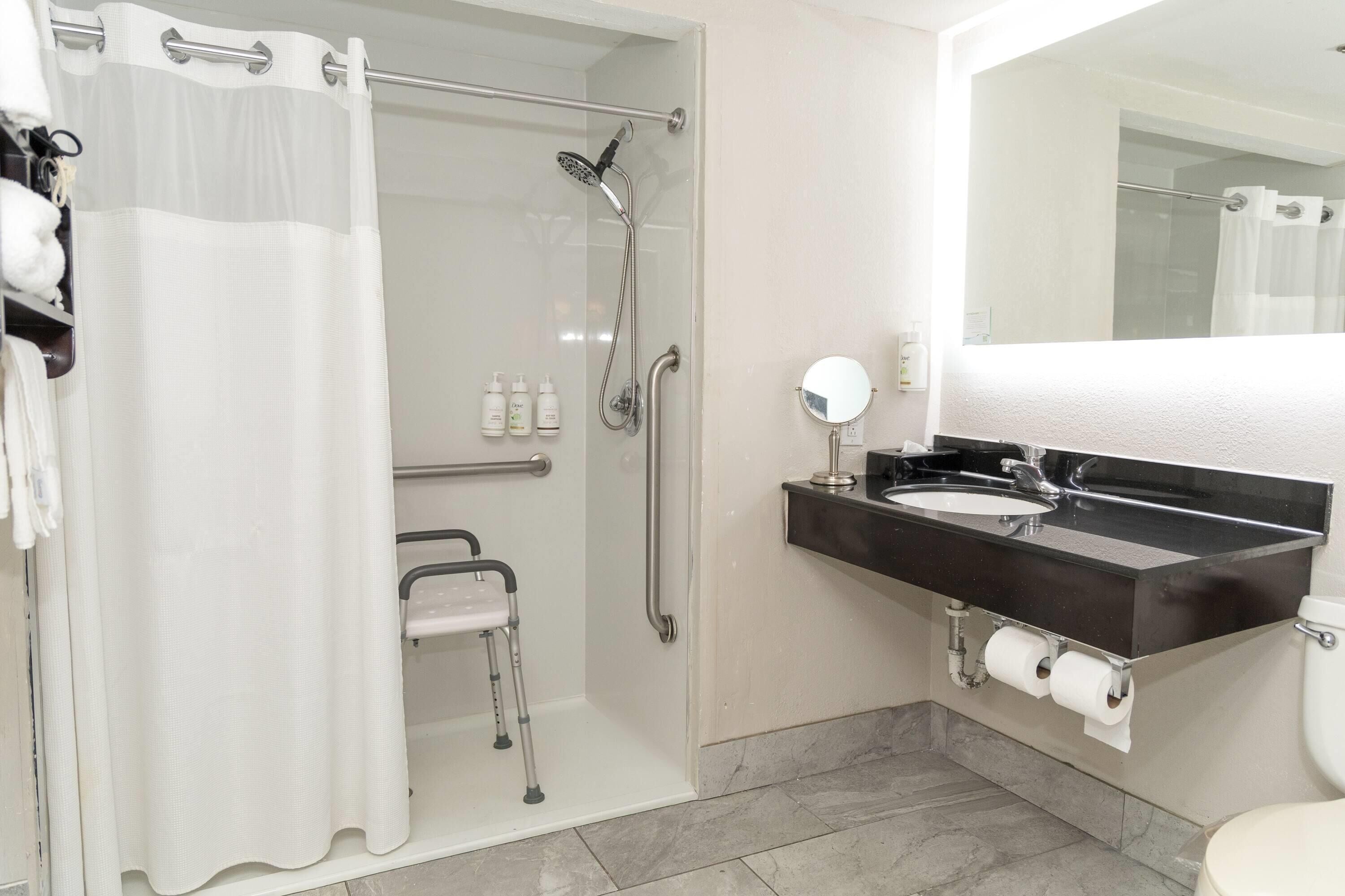 Een badkamer met douche, toilet, wastafel en spiegel.