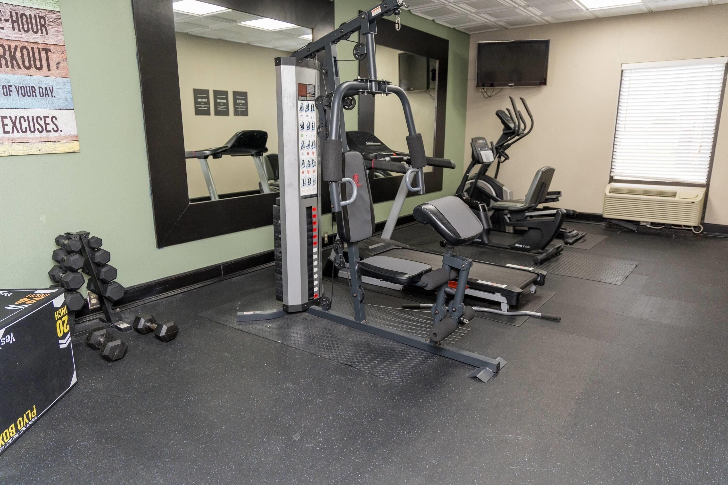 A gym with exercise equipment, a mirror, a TV, and a window.