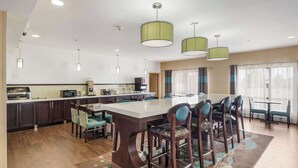 A modern kitchen with dark cabinets, a central island with bar stools, and pendant lighting. - Quality Inn & Suites Quincy - Downtown (Quincy)