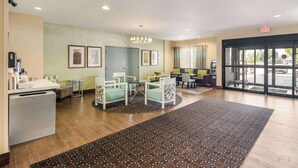 A reception area with a reception desk, seating area with chairs, a patterned rug, and a large window with a view of the outside. - Quality Inn & Suites Quincy - Downtown (Quincy)