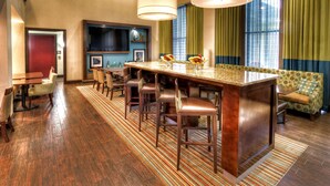 Un hall de hotel con una zona de bar, asientos y un televisor.