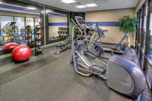 A gym with exercise equipment, a mirror, and a plant. - Hampton Inn Marion (Marion)