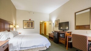 A hotel room with a large bed, a desk with a computer, a television, and a chair. - Hampton Inn Sidney (Sidney)