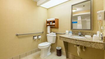 A bathroom with a toilet, sink, mirror, towel rack, and hand dryer.