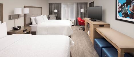 A hotel room with two beds, a desk, a TV, and a large window with curtains.