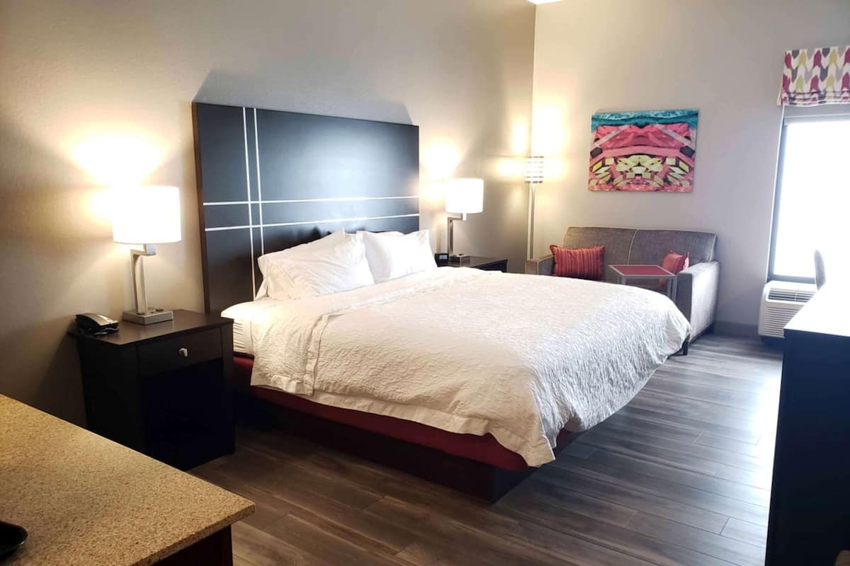 A hotel room with a bed, bedside tables, a desk, and a chair.
