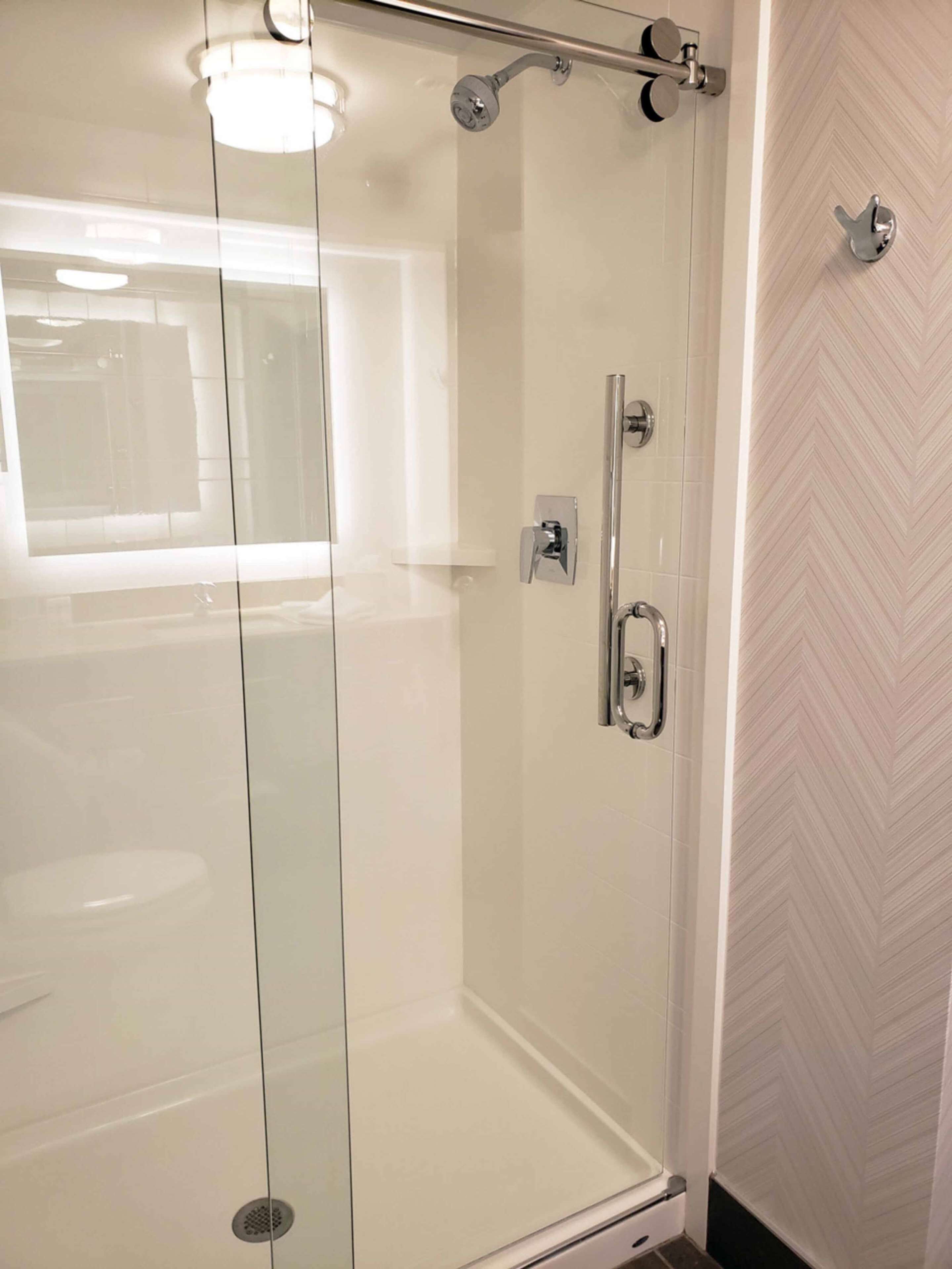 Un baño moderno con cabina de ducha de vidrio, un cabezal de ducha manual y un grifo empotrado en la pared.