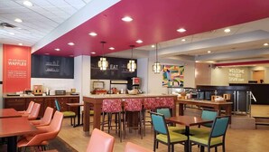 A restaurant with a bar area, seating, and a kitchen.