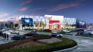 A modern hotel with a prominent 'Live!' sign, featuring a spacious parking lot and landscaped gardens.