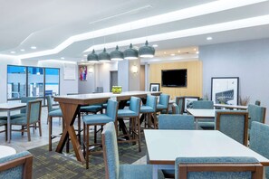 A modern dining area with multiple tables and chairs, a bar counter, and a television mounted on the wall. - Hampton Inn Richmond-Mechanicsville (Mechanicsville)