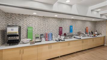 A modern kitchen area with a brick-patterned backsplash, a coffee machine, and various food items on the counter.