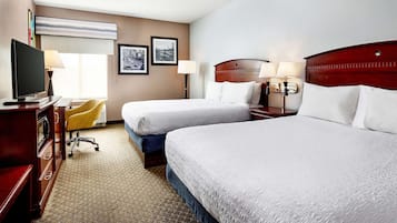 A hotel room with two beds, a desk with a computer, a chair, and a television.