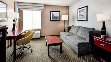 Habitación de hotel con escritorio, silla de oficina, sofá y una mesita.
