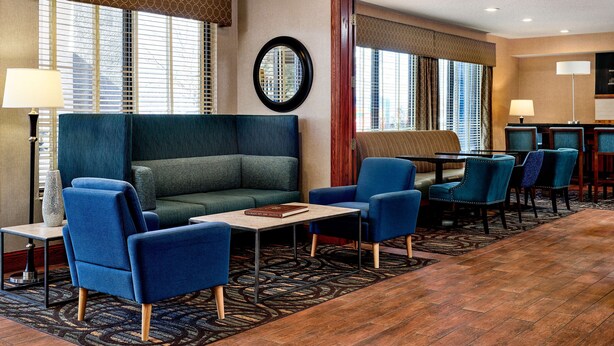 A hotel lobby with a sofa, chairs, a coffee table, and a dining area. - Hampton Inn Longmont (Longmont)