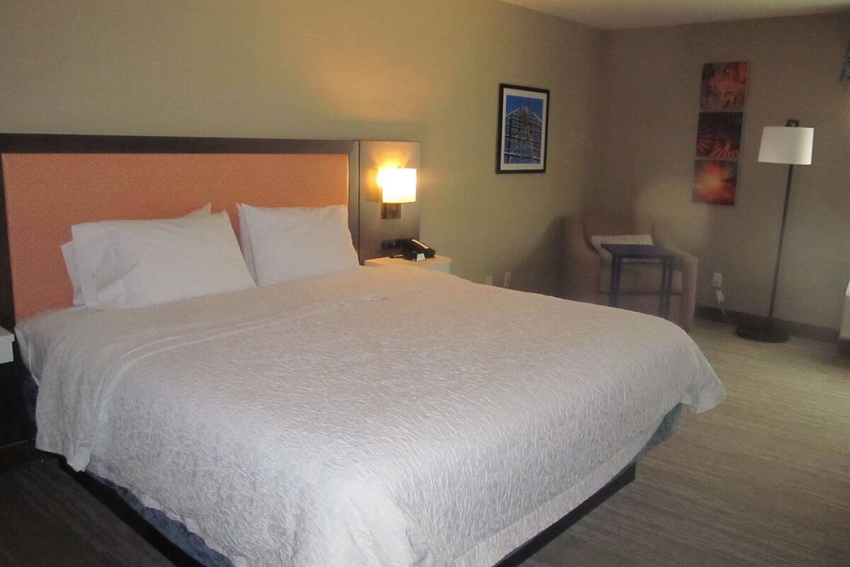 A hotel room with a large bed, a desk, and a chair.