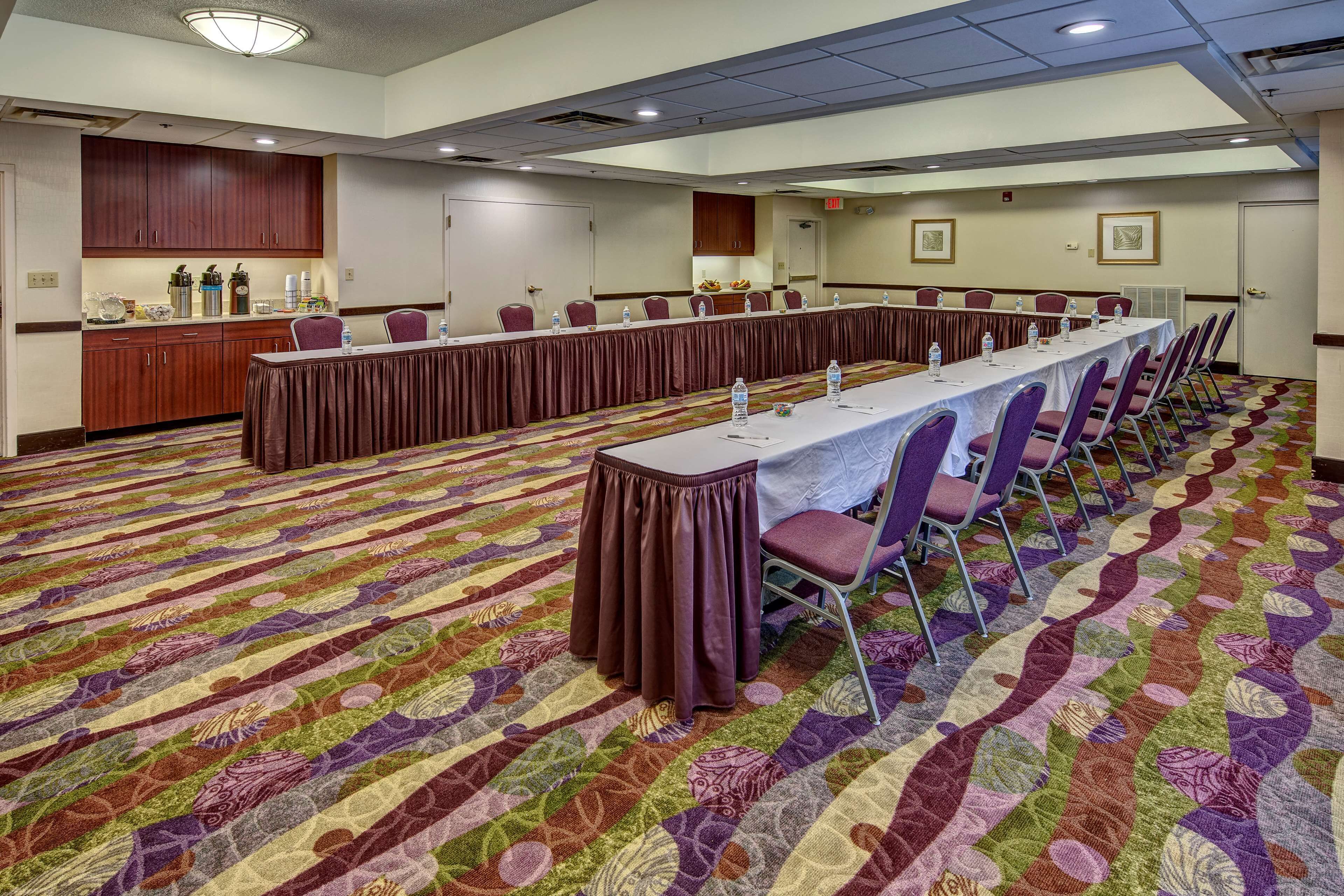 A conference room with a long table, chairs, and a carpeted floor.
