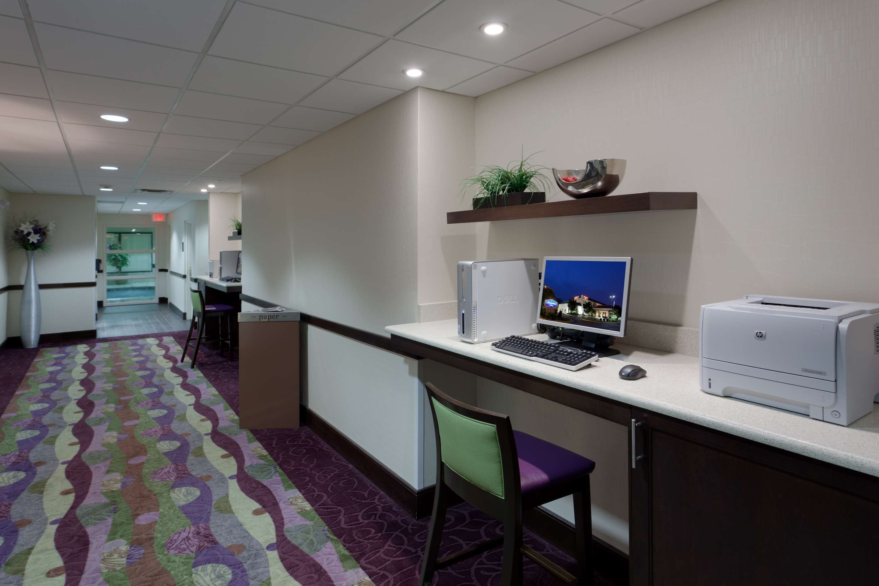 A hotel reception area with a desk, computer, printer, and a patterned carpet.