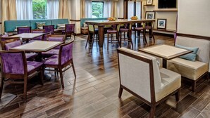 Un restaurante con varias opciones de asientos, incluyendo cabinas y mesas, una gran mesa central con fruta, y un televisor en la pared.