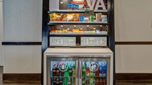 Máquina expendedora con aperitivos y bebidas, un cartel que indica golosinas y el logotipo de VA.