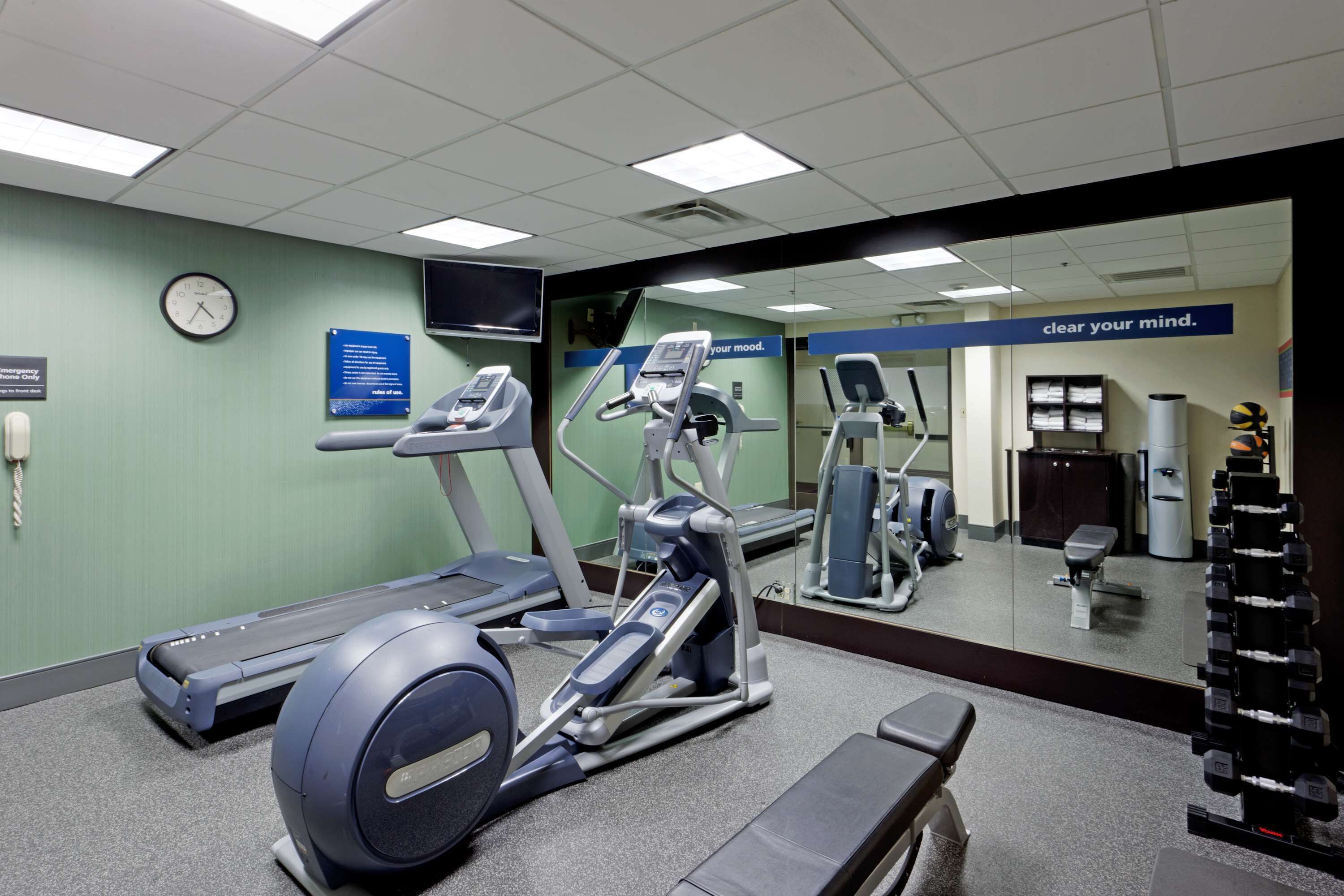 A gym with treadmills, elliptical machines, and a weight rack.