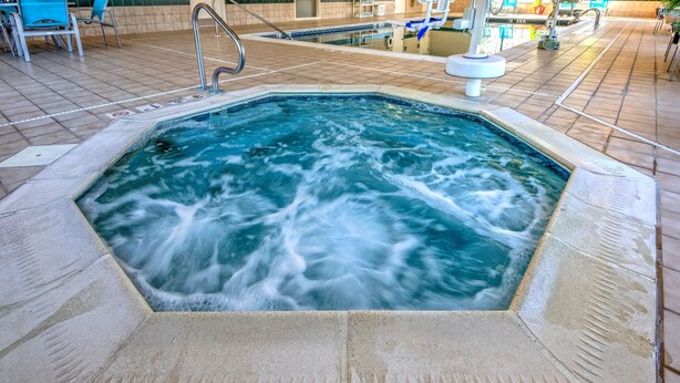 Un jacuzzi con suelo de baldosas y una piscina al fondo.