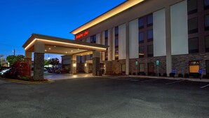 Entrada de hotel con un gran alero, pilares de piedra y un letrero que dice 'Hampton Inn'.