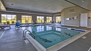 Una piscina con un adhesivo de tiburón, sillas de descanso y vistas al exterior.