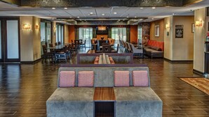 Un vestíbulo de hotel con una zona de estar, un mostrador de recepción y un comedor.