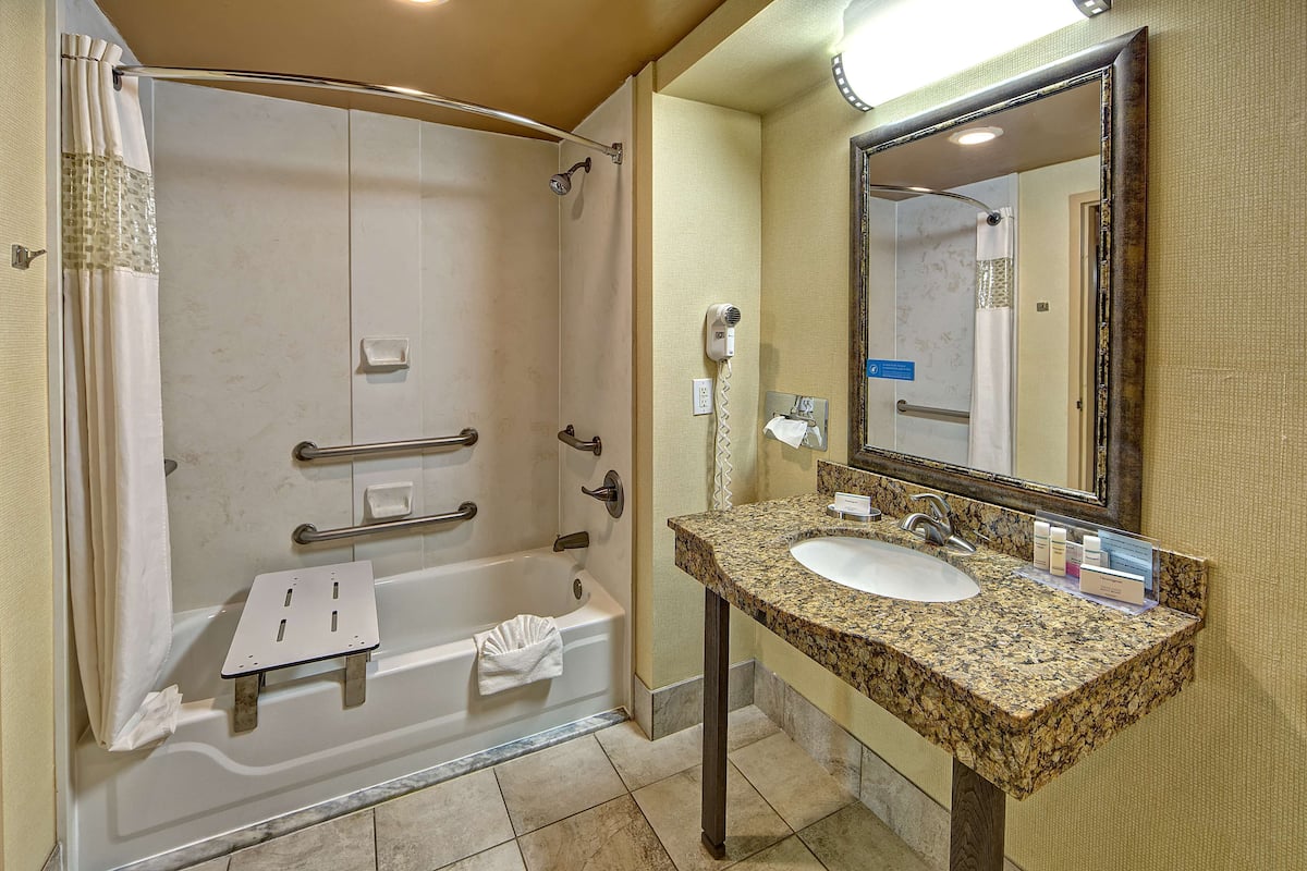 A bathroom with a walk-in shower, a sink, and a vanity mirror.