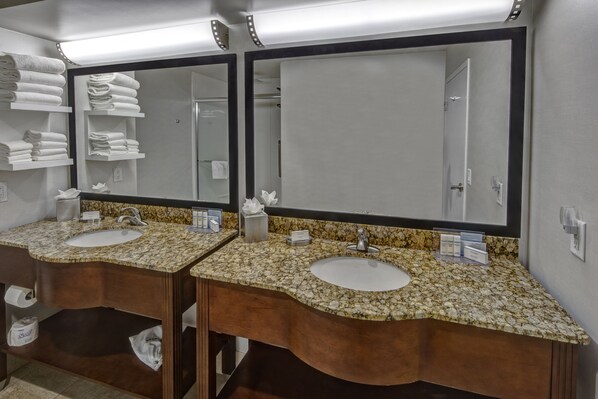 Un baño con dos lavamanos, espejos grandes y toalleros.