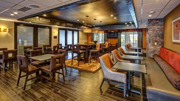 Un restaurante con varias zonas de comedor, incluyendo cabinas y mesas, con una decoración interior moderna y una pantalla grande en la pared.