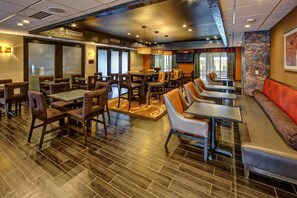 A restaurant with multiple dining areas, including booths and tables, with a modern interior design and a large screen on the wall. - Hampton Inn Indianapolis-sw/plainfield (Plainfield)