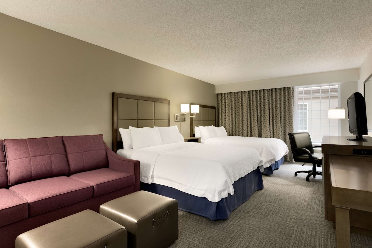 A hotel room with a large bed, a sofa, a desk, and a chair.