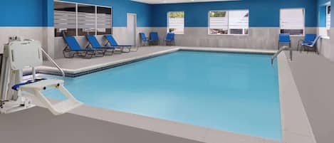 Una piscina interior con sillas azules y una silla para salvavidas.